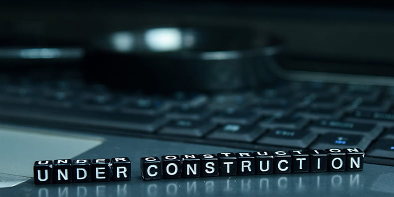 A Laptop with Black Dice Saying Under Construction